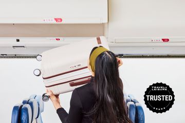 Person lifting the Samsonite Virtuosa Expandable Carry-on into an overhead bin