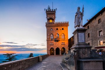 The Palazzo Pubblico (Public Palace, Town Hall) and the Statua della LibertÃ  (Statue of Liberty) by Stefano Galletti (1876) at twilight
