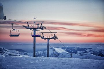 A ski lift on a snowy mountain at sunrise in Georgia