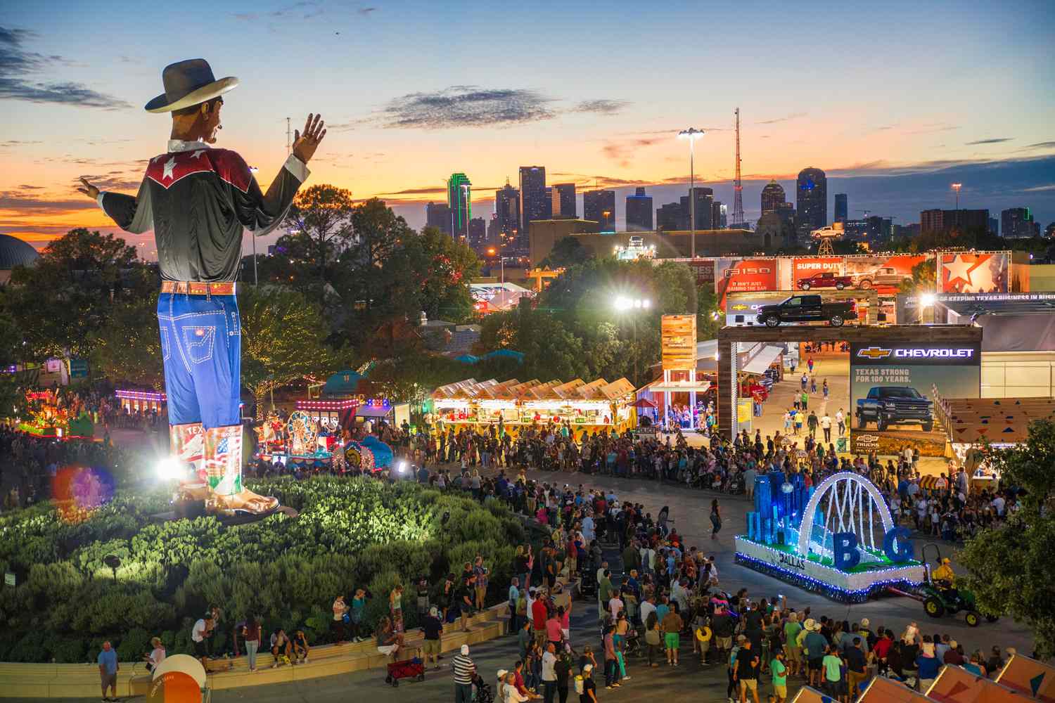 Aerial view of Big Tex and the crowds in the evening with the skyline of Dallas in the distance