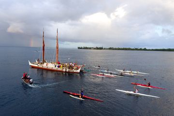 Kayaks escort the canoe out to sea 