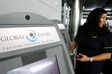 Lizzethe Escoto of Continental Airlines looks over at a friend who has to use the Customs line as she uses a Global Entry kiosk to enter the country 