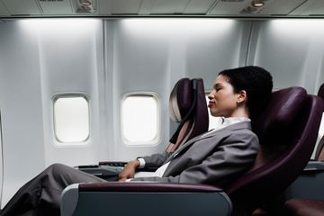 Woman sleeping on reclining airplane seat 
