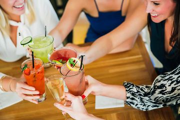 Women toasting at bar with cocktails